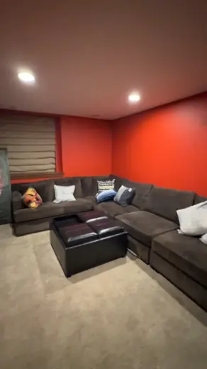 Basement with orange accent wall and dark sectional, Elements Painting project on the Colorado Front Range