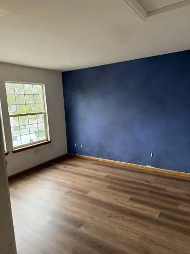 Bedroom with navy accent wall and light wood flooring, Elements Painting project on the Colorado Front Range