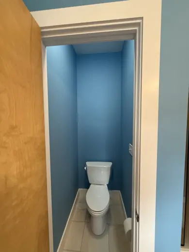 Blue painted bathroom with white toilet, tan hallway, Elements Painting project on the Colorado Front Range