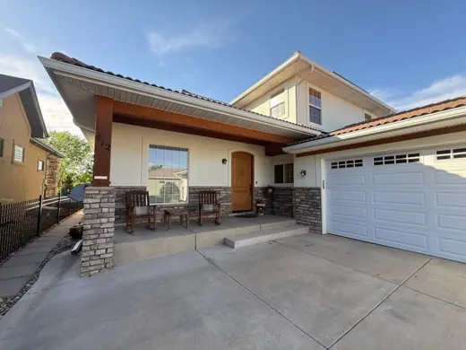 Cream stucco home with stone columns and white garage, Elements Painting project on the Colorado Front Range