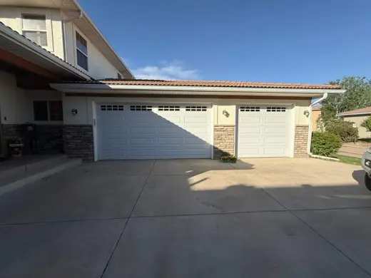 Cream stucco home with white double garage doors, Elements Painting project on the Colorado Front Range