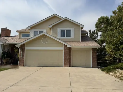 Cream two-story home with three-car garage, brick accents, Elements Painting project on the Colorado Front Range