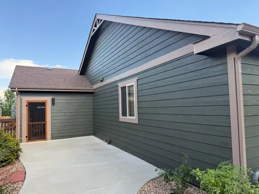 Dark green home with tan trim and concrete patio, Elements Painting project on the Colorado Front Range