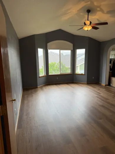 Empty room with arched window, ceiling fan, hardwood floors, Elements Painting project on the Colorado Front Range