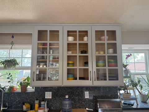 Cabinet painting, light grey glass-front upper cabinets, dark granite backsplash, kitchen, Elements Painting project on the Colorado Front Range