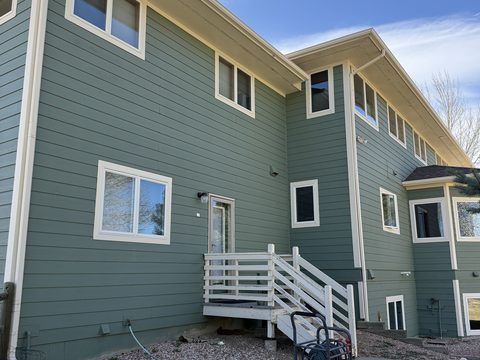 Exterior painting, rear of sage green two-story home, white window trim, small white deck stairs, Elements Painting project on the Colorado Front Range
