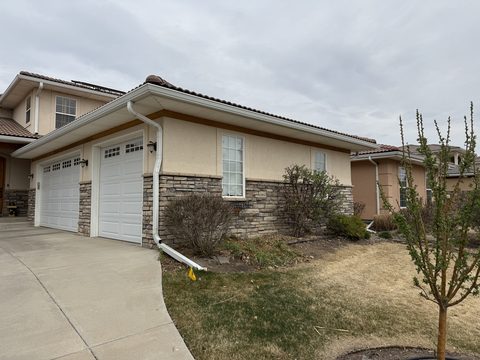 Exterior painting, beige stucco, stone wainscot, white garage doors, Elements Painting project on the Colorado Front Range