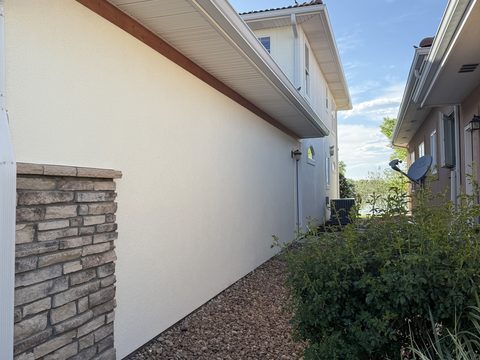 Exterior painting, cream stucco side wall with stone wainscot, white soffit, gravel bed, Elements Painting project on the Colorado Front Range