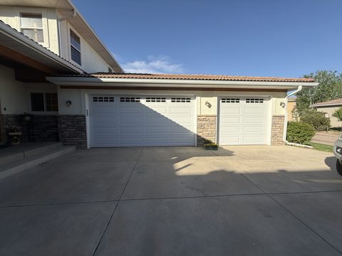 Exterior painting, cream stucco three-car garage, white doors, stone accents, driveway, Elements Painting project on the Colorado Front Range