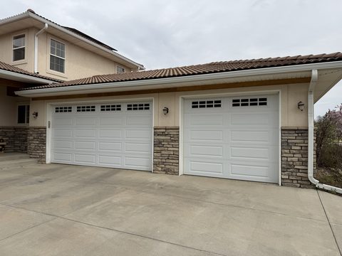 Exterior painting, beige stucco home, three white garage doors, stone veneer base, Elements Painting project on the Colorado Front Range