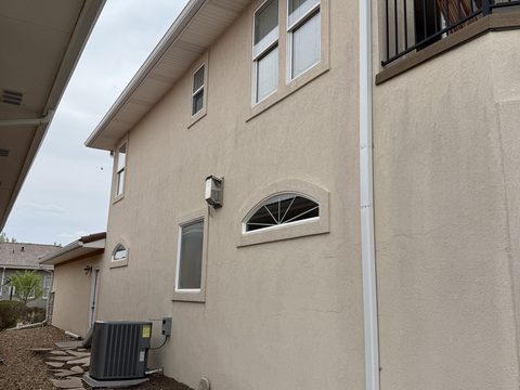 Exterior painting, beige stucco side wall with white trim and downspout, Elements Painting project on the Colorado Front Range