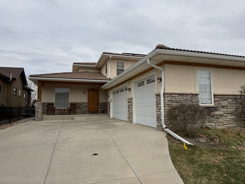 Exterior painting, beige stucco home front, white double garage doors, stone base, Elements Painting project on the Colorado Front Range