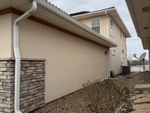 Exterior painting, beige stucco side wall, stone base, downspout, gravel yard, Elements Painting project on the Colorado Front Range