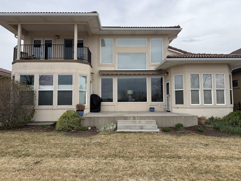 Exterior painting, rear of beige stucco home, balcony, large windows, concrete patio, Elements Painting project on the Colorado Front Range