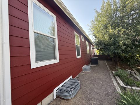 Exterior painting, barn-red lap siding side wall, white trim, window wells, garden beds, Elements Painting project on the Colorado Front Range