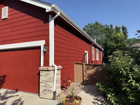 Exterior painting, red siding garage side, white trim, brick pillar, wood gate, sunny, Elements Painting project on the Colorado Front Range