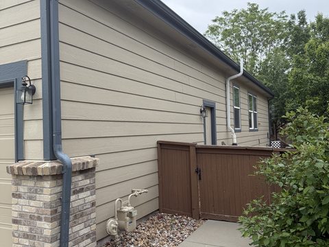 Before painting: Tan siding garage side, blue-grey trim, brown gate, Elements Painting project on the Colorado Front Range