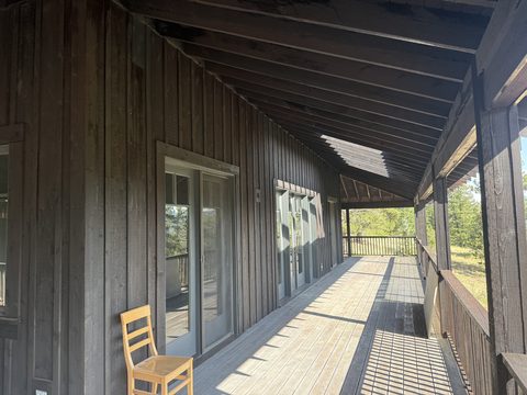 Exterior painting, covered porch with dark stained siding, grey french doors, wooden chair, lodge-style home, Elements Painting project on the Colorado Front Range