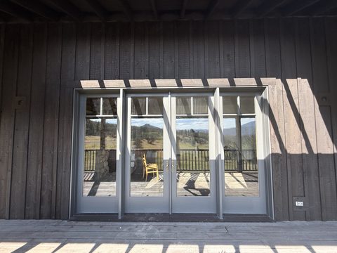 Exterior painting, grey-trimmed glass french doors on dark brown board-and-batten wall, mountain reflection, Elements Painting project on the Colorado Front Range