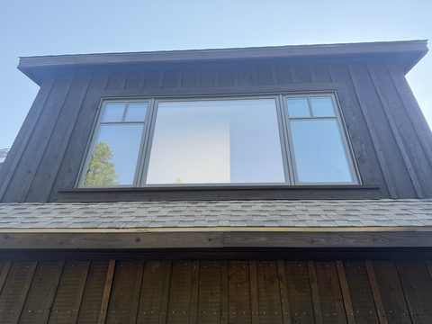 Exterior painting, dormer with dark brown siding and grey-trimmed picture windows, shingle roof, Elements Painting project on the Colorado Front Range