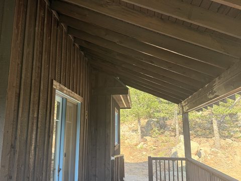 Exterior painting, porch corner with dark stained rafters, grey door trim, white railing, rocky hillside, Elements Painting project on the Colorado Front Range