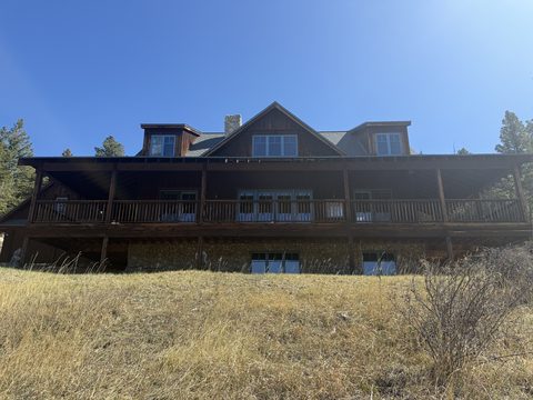 Exterior painting, of brown lodge with wraparound deck on grassy hillside, Elements Painting project on the Colorado Front Range
