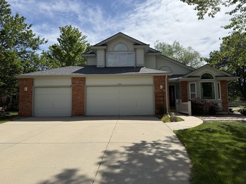 Exterior painting, two-story grey house, brick accents, white garage doors, Elements Painting project on the Colorado Front Range