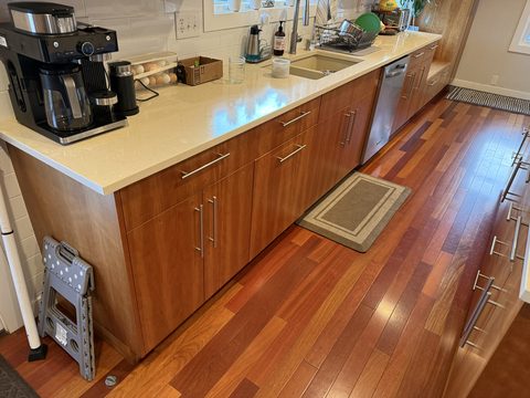 Cabinet painting, kitchen with warm cherry-stained flat-panel cabinets, cream quartz counter, hardwood floor, Elements Painting project on the Colorado Front Range
