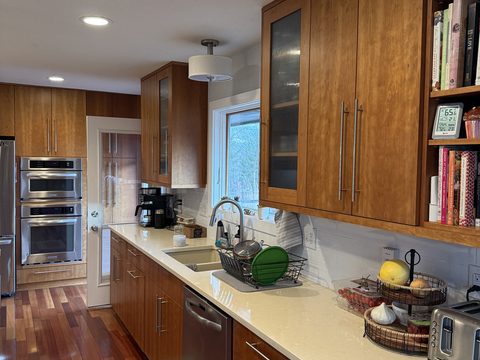 Cabinet painting, galley kitchen, medium-wood cabinets with glass uppers, white subway backsplash, stainless appliances, Elements Painting project on the Colorado Front Range