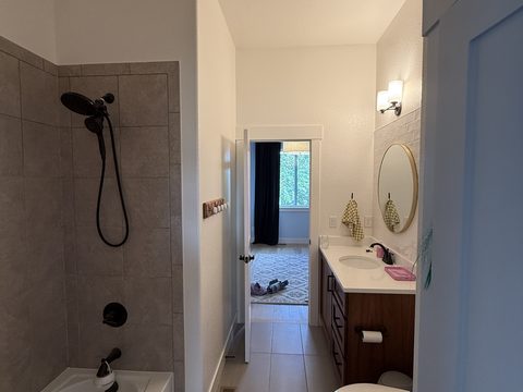 Interior painting, bathroom with white walls, gray tiled shower, dark wood vanity, round mirror, Elements Painting project on the Colorado Front Range