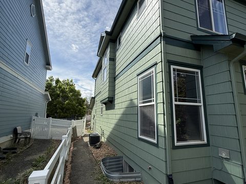 Exterior painting, side elevation, sage-green lap siding, white window trim, white fence, Elements Painting project on the Colorado Front Range