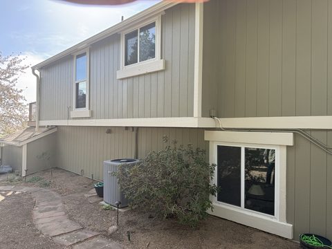 Exterior painting, olive-tan vertical siding, white trim windows, rear elevation, Elements Painting project on the Colorado Front Range