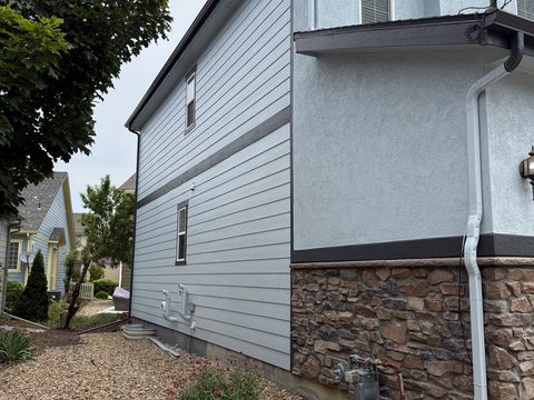 Exterior painting, light blue siding side wall, dark gray band trim, stone wainscot, Elements Painting project on the Colorado Front Range