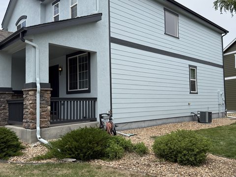 Exterior painting, pale blue siding, dark trim porch with stone columns, side yard, Elements Painting project on the Colorado Front Range