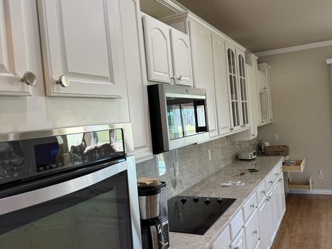 Cabinet painting, white kitchen cabinets angled view, tape and supplies on counter, Elements Painting project on the Colorado Front Range