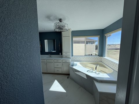 Interior painting, dark blue bathroom walls, cream cabinets, corner tub, large windows, Elements Painting project on the Colorado Front Range
