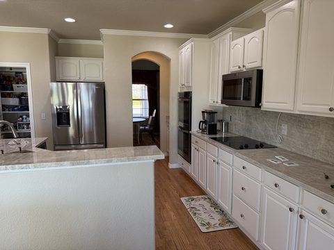Cabinet painting, white kitchen cabinets, granite counters, beige walls, stainless appliances, wood floor, Elements Painting project on the Colorado Front Range