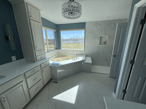 Interior painting, primary bath, deep blue walls, white cabinets, marble floor, soaking tub, chandelier, Elements Painting project on the Colorado Front Range