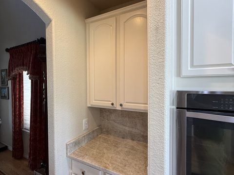 Cabinet painting, white upper cabinets in kitchen nook, tile counter, beige textured walls, Elements Painting project on the Colorado Front Range