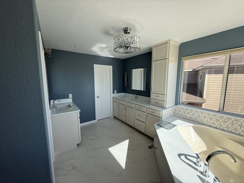 Interior painting, primary bath, dark blue walls, white vanity and linen cabinets, marble floor, Elements Painting project on the Colorado Front Range