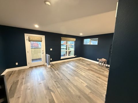 Interior painting, empty room, navy walls, white trim, light wood floor, balcony door, bamboo shades, Elements Painting project on the Colorado Front Range