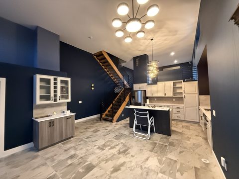 Interior painting, open kitchen and living room, navy walls, cream cabinets, marble tile floor, modern pendants, open stair, Elements Painting project on the Colorado Front Range