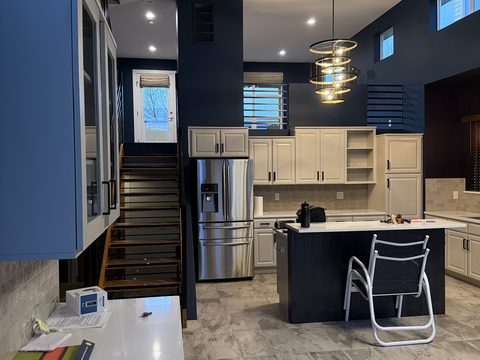 Interior painting, kitchen with navy walls, cream cabinets, stainless fridge, dark island, Elements Painting project on the Colorado Front Range