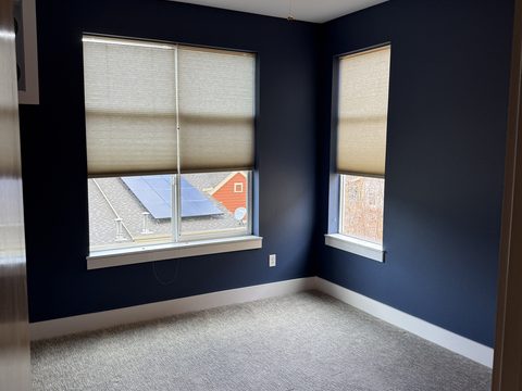 Interior painting, navy blue bedroom corner, two windows with shades, grey carpet, Elements Painting project on the Colorado Front Range