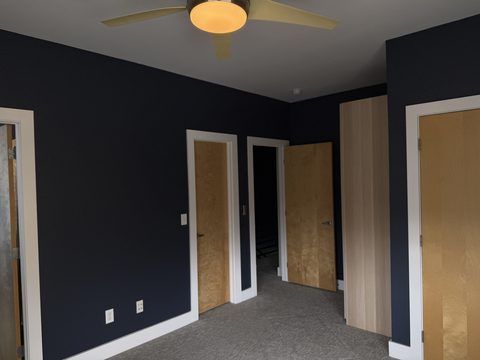 Interior painting, dark navy bedroom with birch doors and wardrobe, ceiling fan, Elements Painting project on the Colorado Front Range