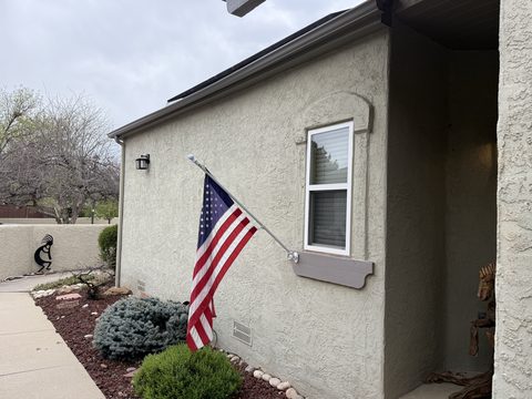 Exterior painting, tan stucco exterior with American flag, window trim, landscaping, Elements Painting project on the Colorado Front Range