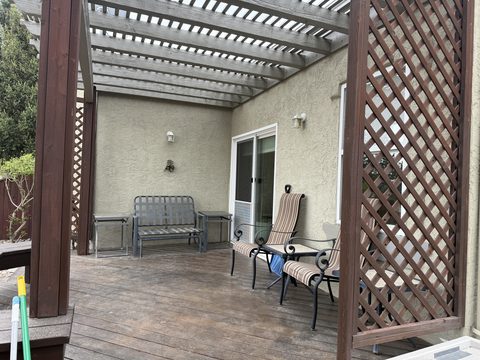 Exterior painting, tan stucco wall under pergola, wood deck, lattice, patio furniture, Elements Painting project on the Colorado Front Range