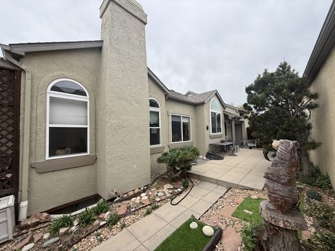 Exterior painting, tan stucco rear elevation with chimney, patio, rock landscaping, Elements Painting project on the Colorado Front Range
