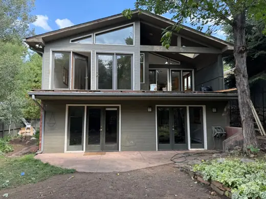 Faded dark green home before repainting, large windows, sloped lot, Elements Painting project on the Colorado Front Range