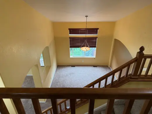 Landing with wood banister, yellow walls before repainting, Elements Painting project on the Colorado Front Range